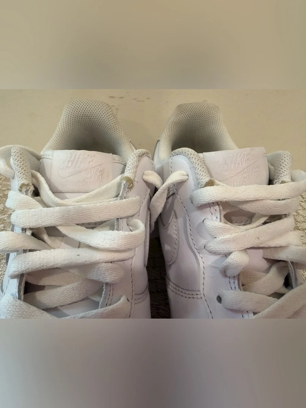 These are iconic Nike Air Force 1 sneakers in an all-white colorway.